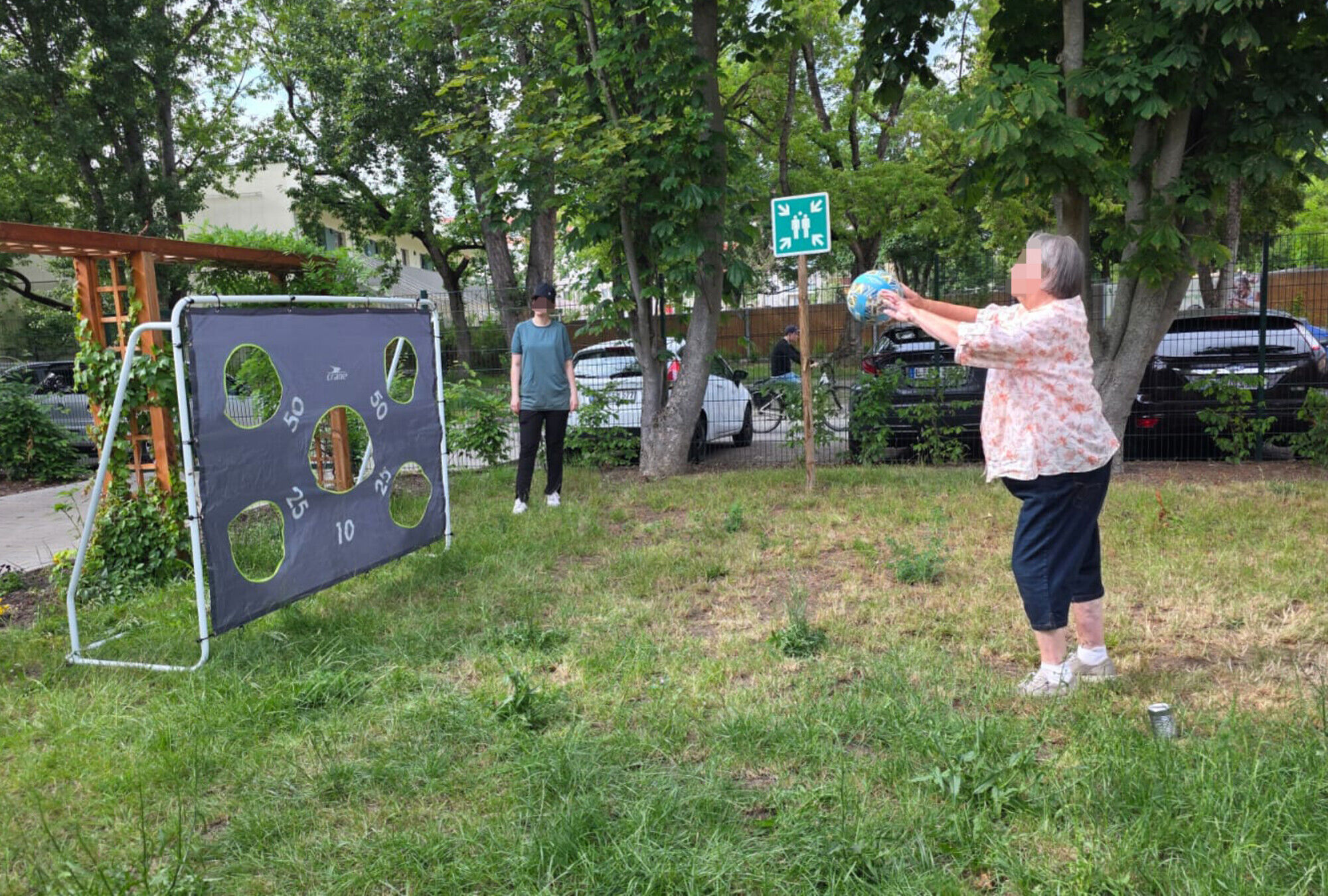 Eine Frau wirft mit einem Ball auf ein Tor mit unterschiedlichen L&ouml;chern und Punkten