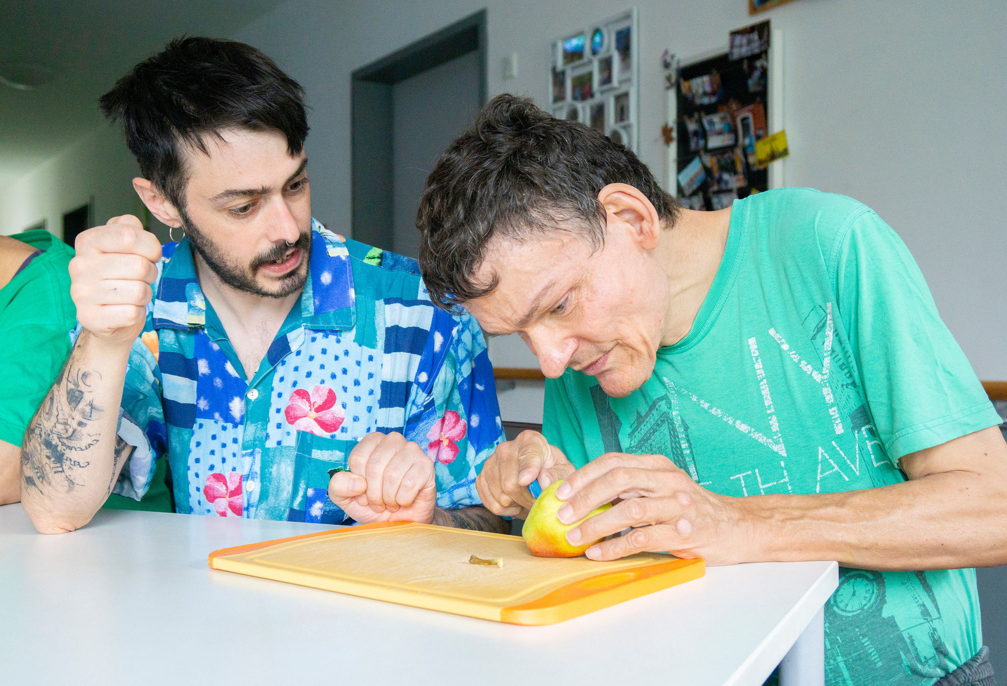Ein Mann schneidet eine Birne, ein anderer Mann schaut zu