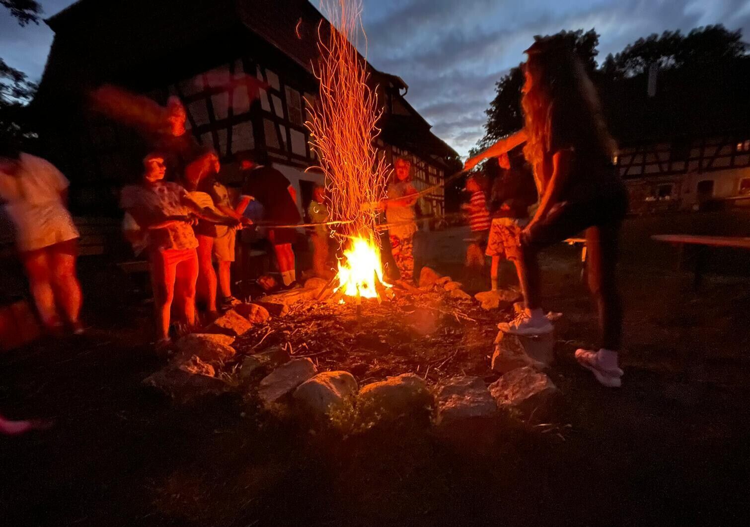 © SEB Leipzig Kinder stehen um ein Lagerfeuer mit Stöcken an der Hand und halten diese ins Feuer