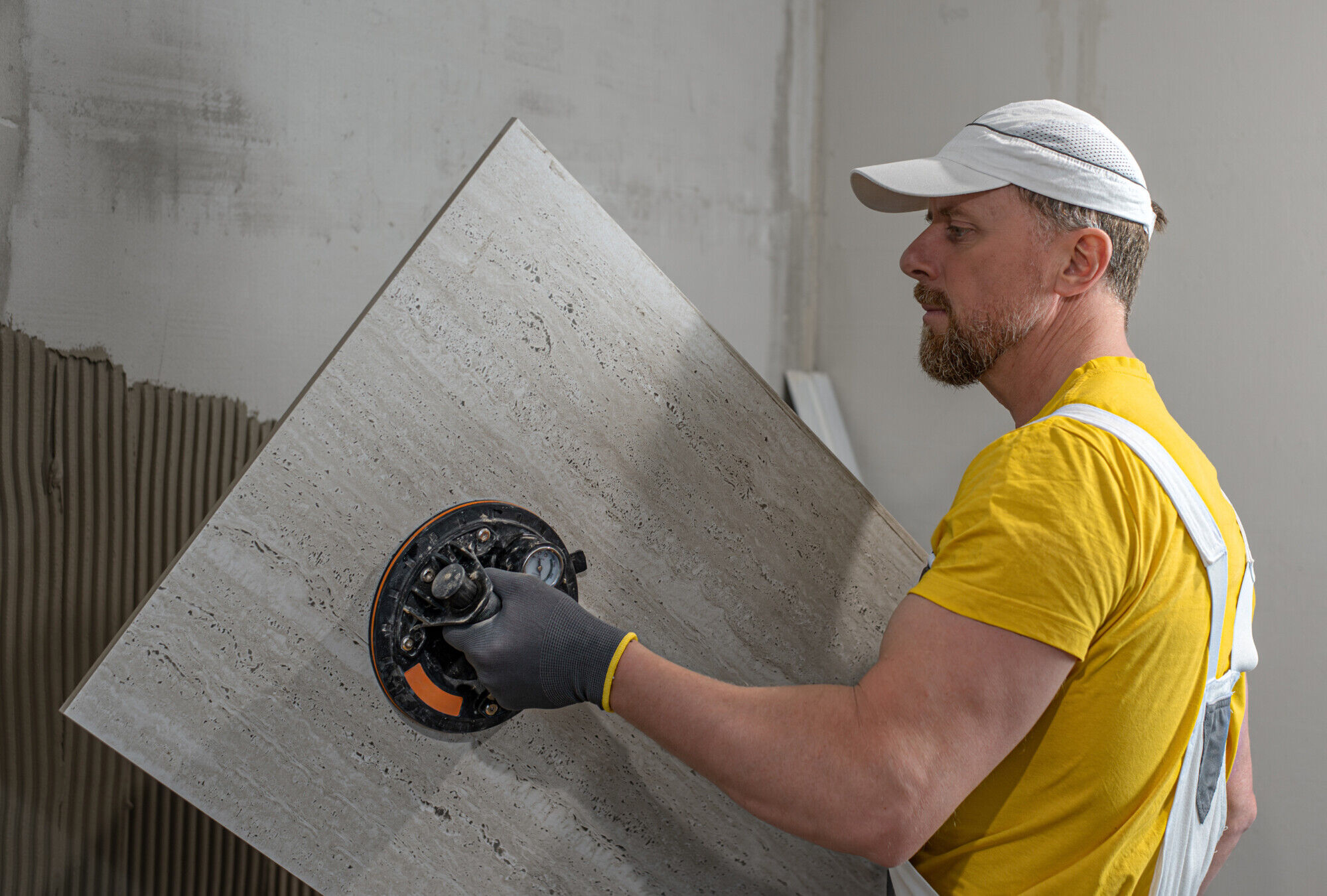 Handwerker beim Anbringen einer gro&szlig;en Fliese an die Wand