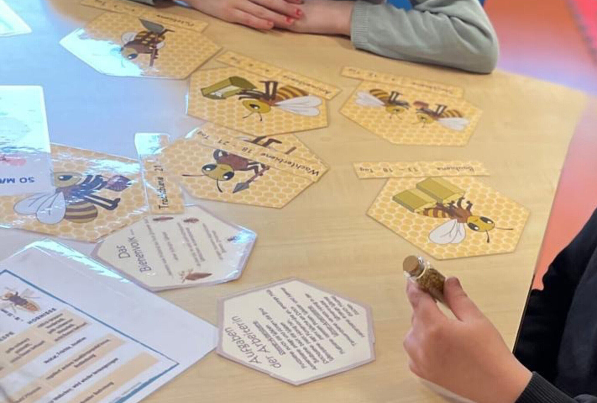 auf einem Tisch liegen Karten mit Text, Bienen und Wabenmotiven