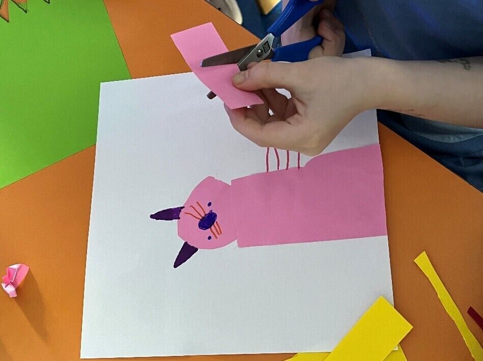 © SEB Leipzig Ein Kind schneidet aus Tonpapier eine Katze aus
