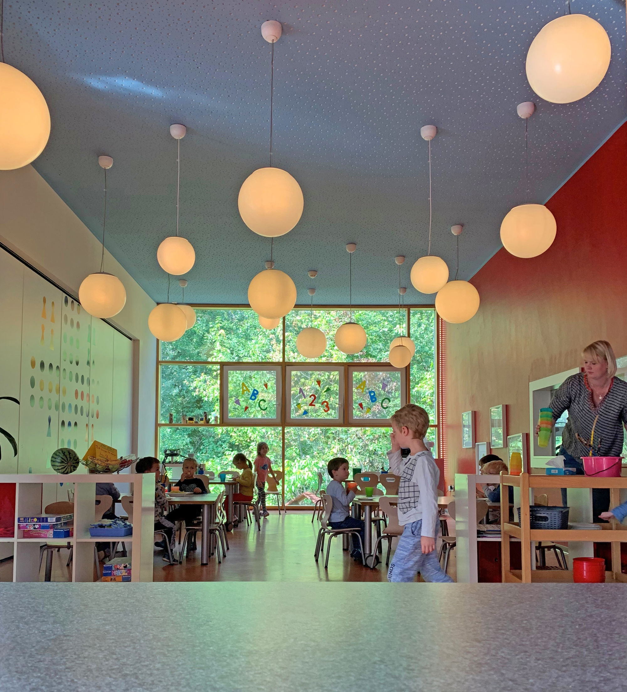 Der Speiseraum mit tischen und Stühlen und vielen großen Kugellampen, die von der Decke hängen.