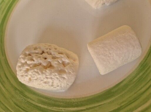 zwei Marshmallows auf einem Teller. Einer davon viel gr&ouml;&szlig;er als der andere