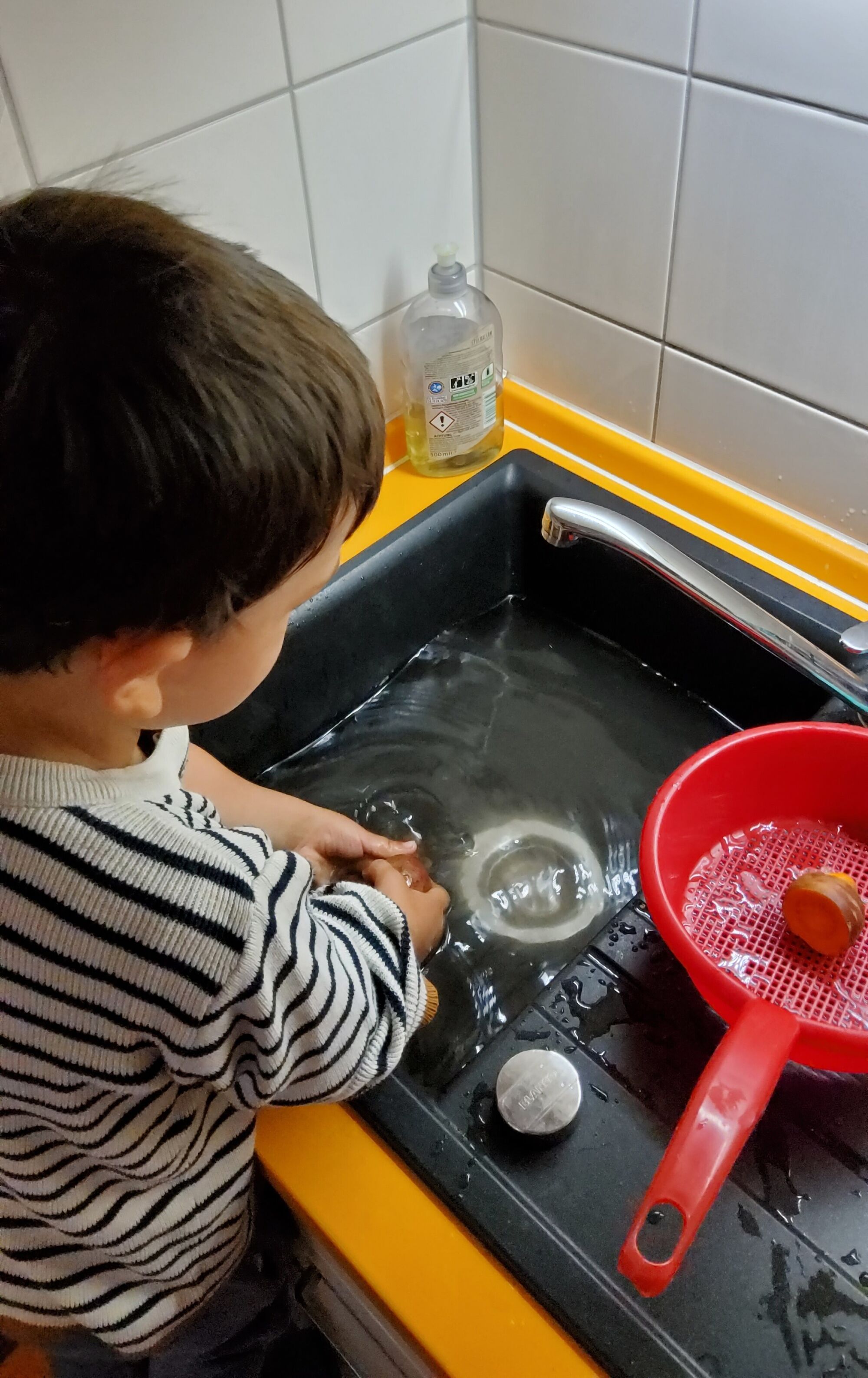 Ein Junge wäscht Gemüse