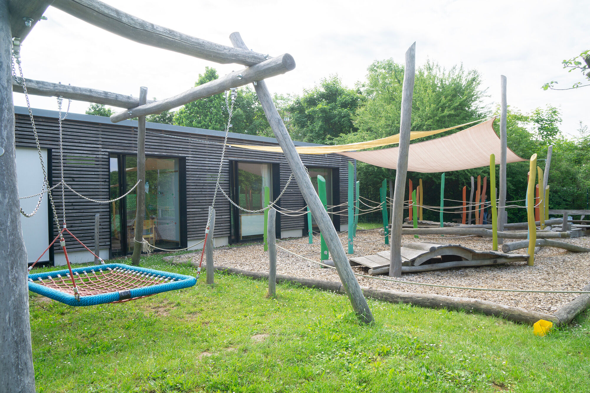 eine große Nestschaukel, ein Parcours aus Holzbalken und Matten zu Klettern und balancieren