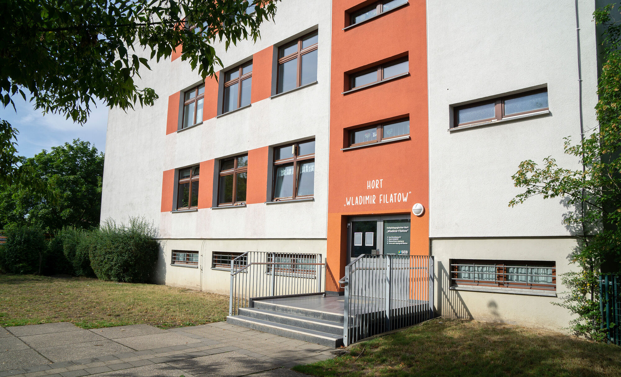 Ein großes weiß-rotes Gebäude mit einer Treppe zum Eingang.
