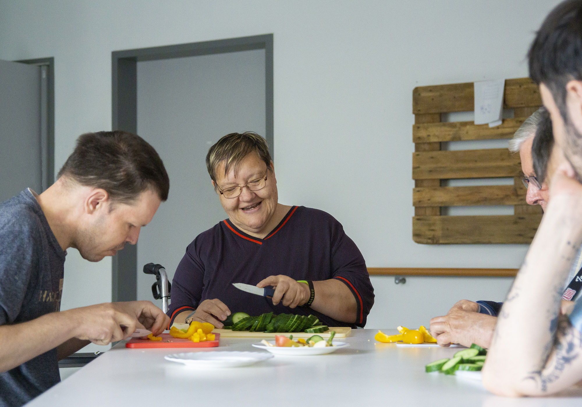 Menschen sitzen an einem Tisch und schneiden Gemüse