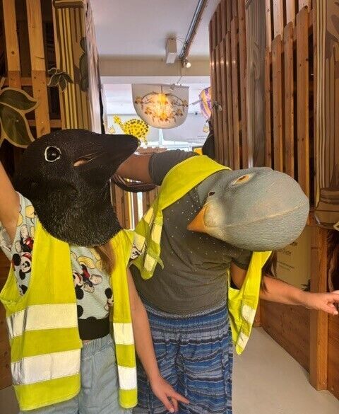 Kinder mit Vogelmasken schauen sich an