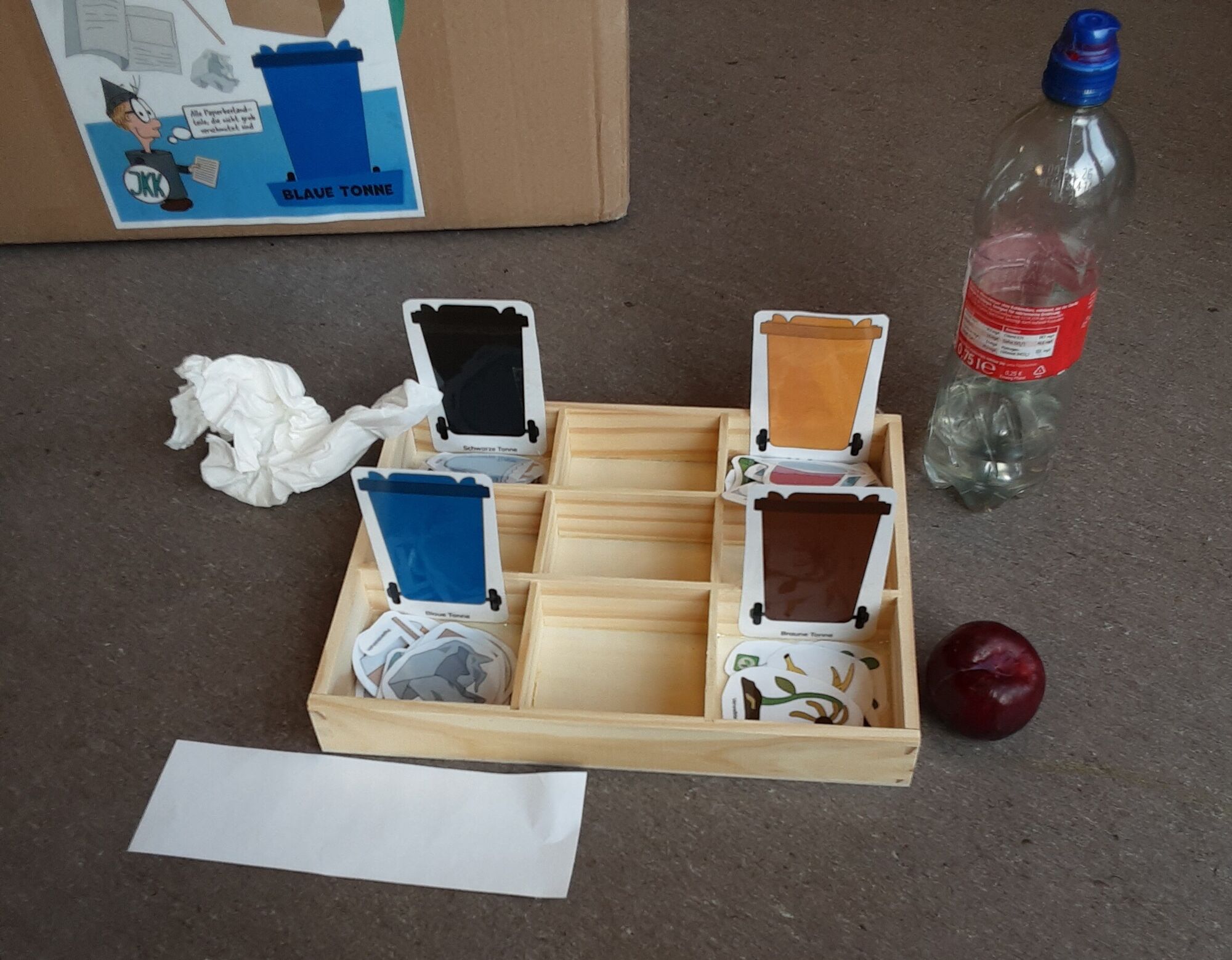 Eine Kiste mit gebastelten M&uuml;lltonnen und dazugeh&ouml;rigem M&uuml;ll
