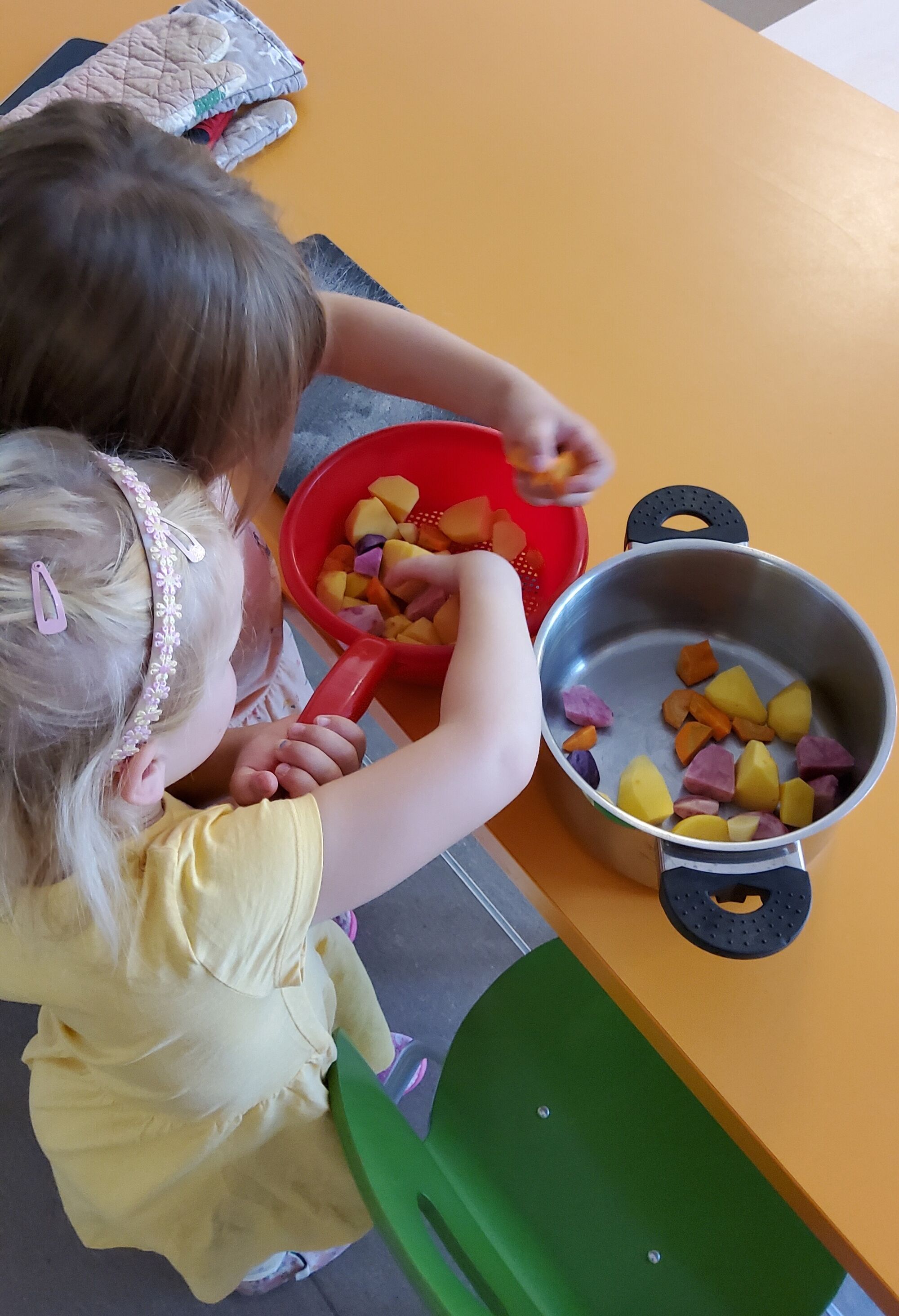 Zwei Kinder füllen geschältes Gemüse in einen Topf