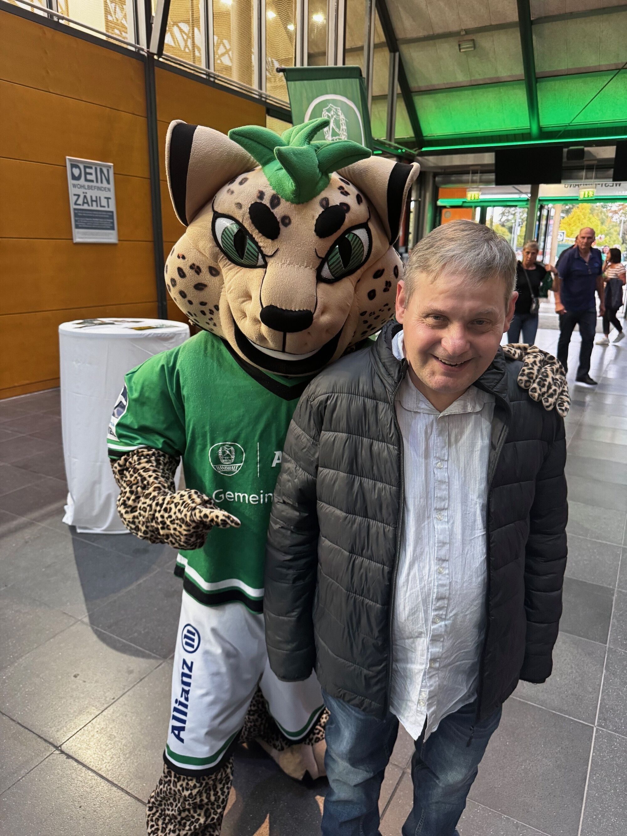 Ein Mann steht neben dem Maskottchen
