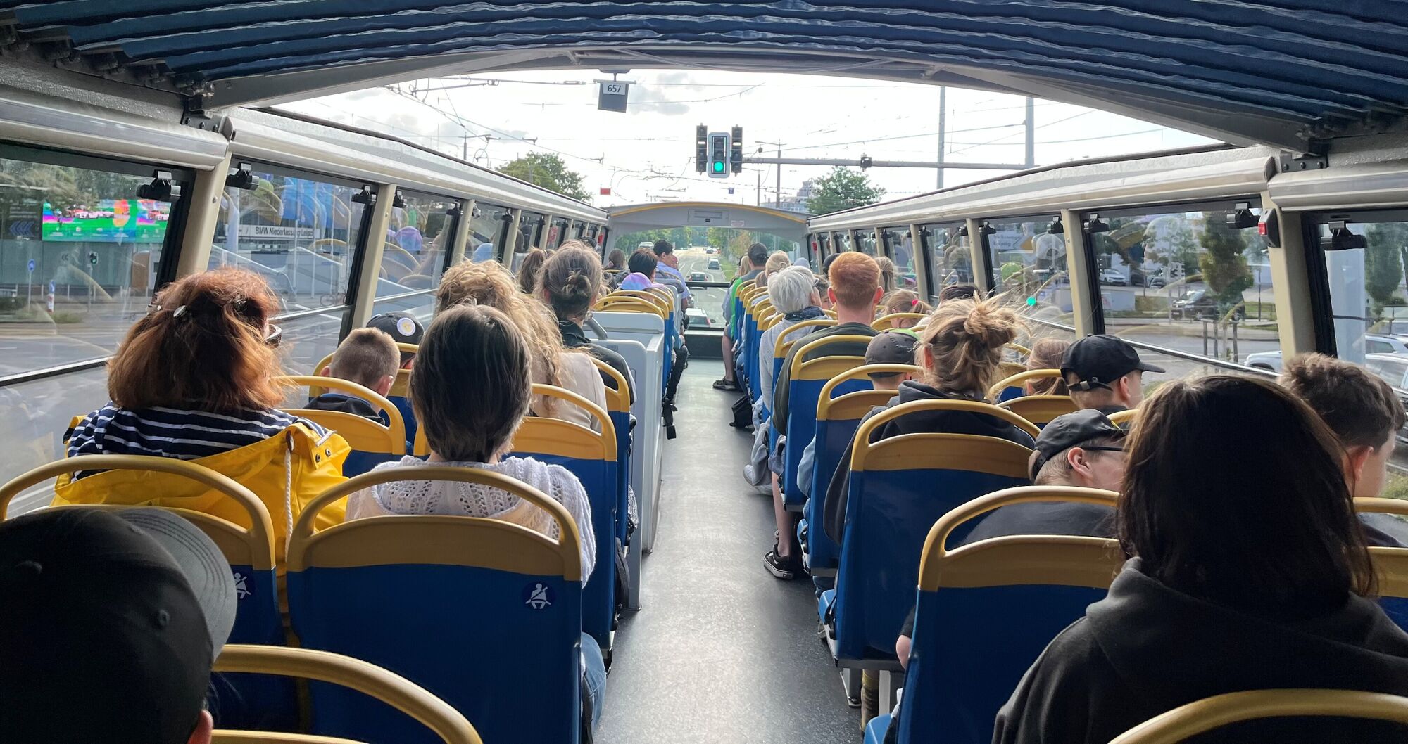 Viele Menschen sitzen im oberen teil des Busses, der unter einer Brücke hindurch fährt