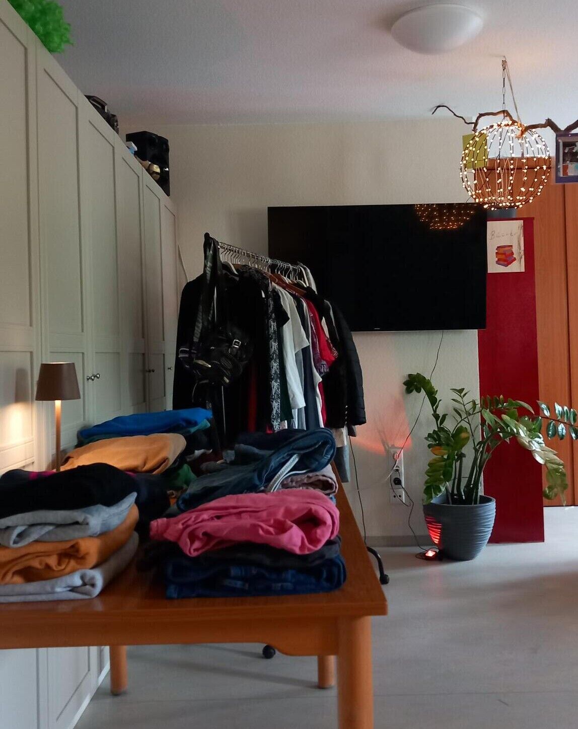 © SEB Leipzig Neben dem Kleiderständer ist ein Tisch mit vielen Kleidungsstücken.