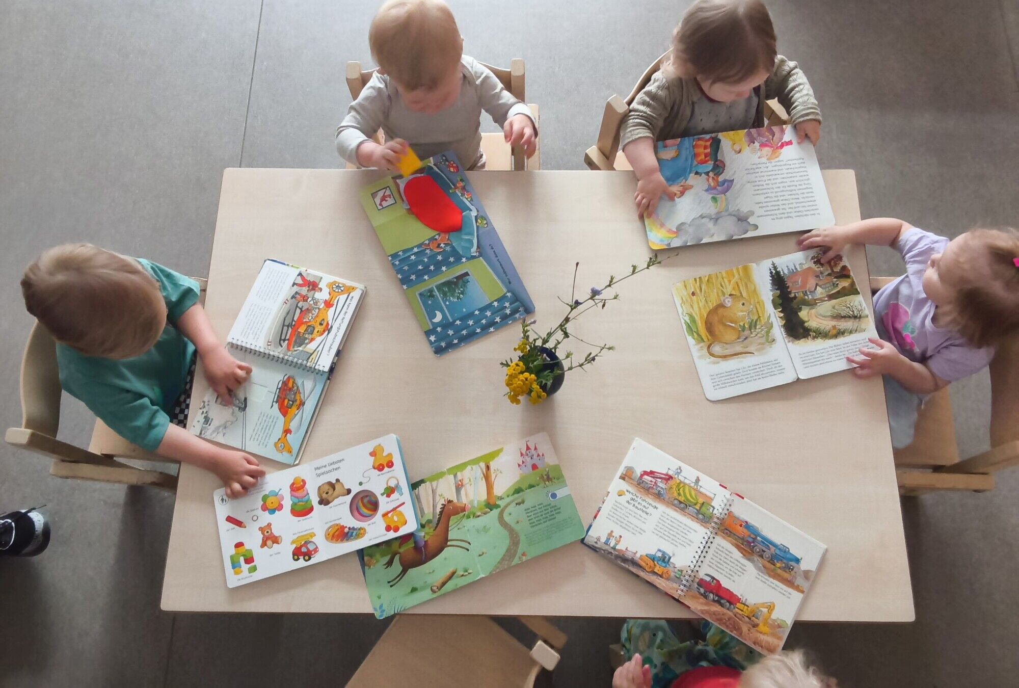 Kinder sitzen an einem Tisch mit B&uuml;chern