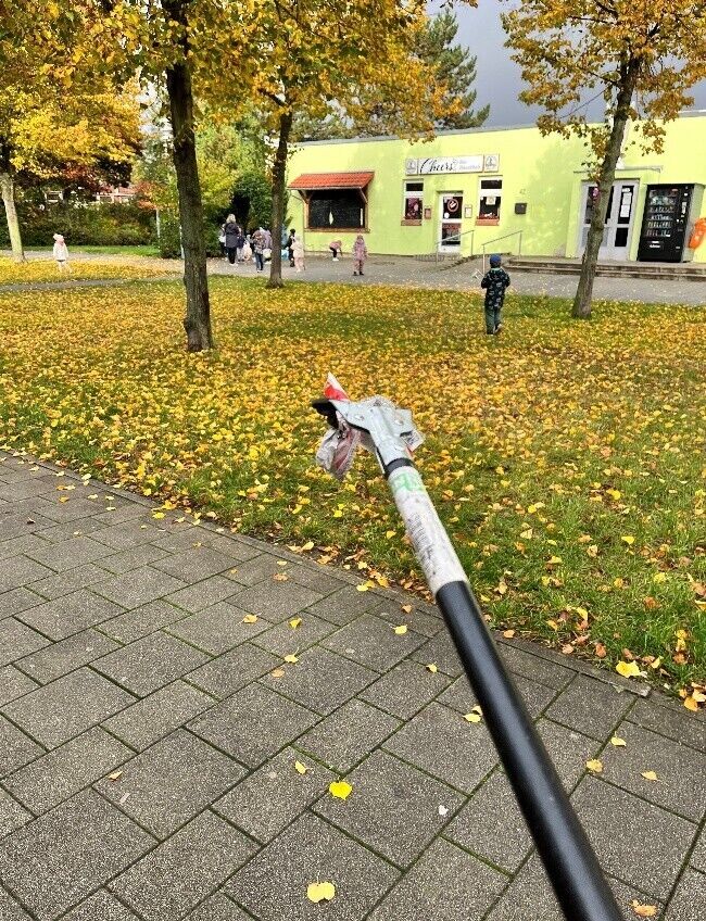 Ein Müllgreifer mit Müll und Kinder im Hintergrund