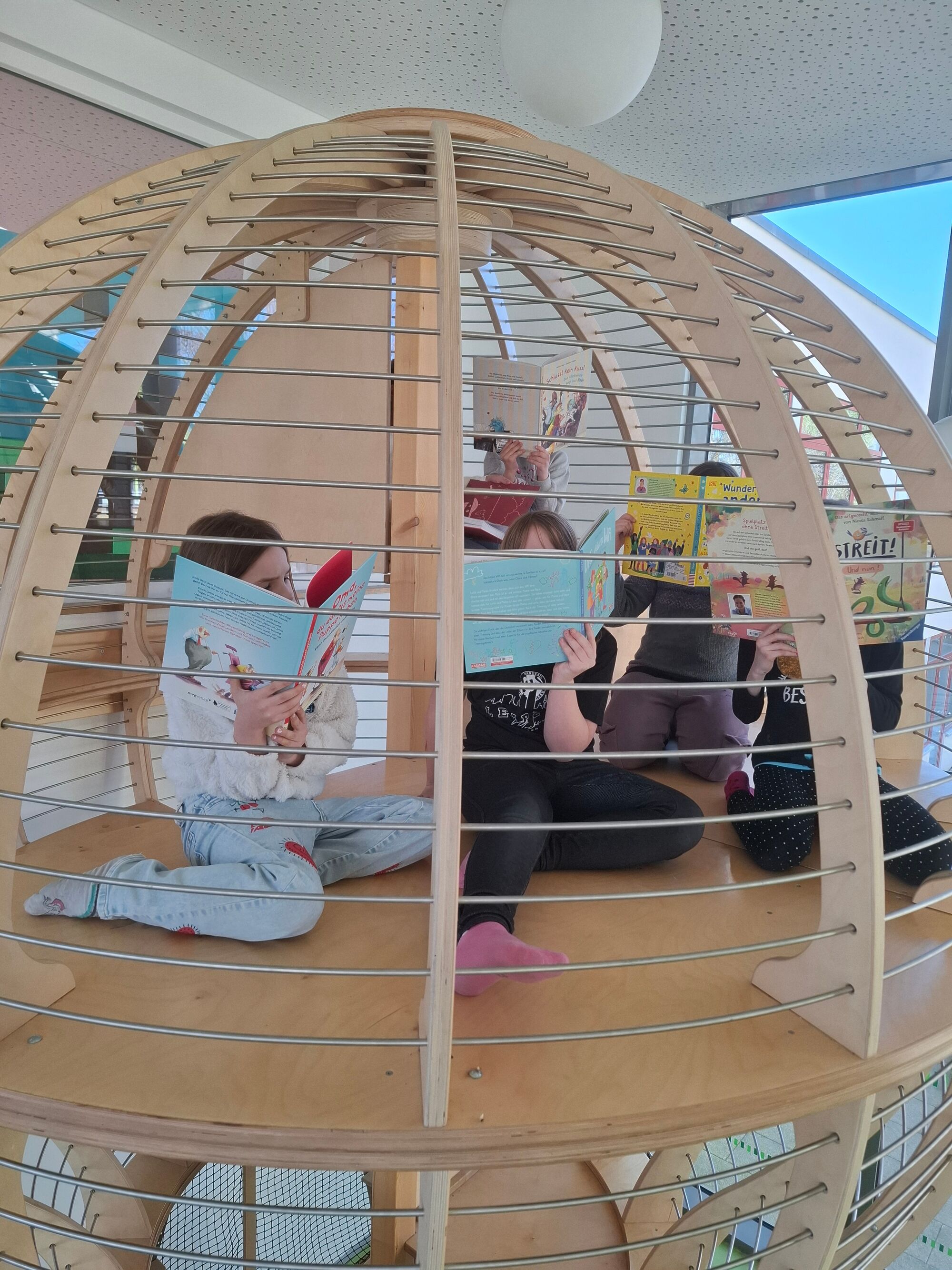 Kinder sitzen in einem Kltterger&uuml;st in Form eines riesigen Hei&szlig;luftballons und schauen sich B&uuml;cher an