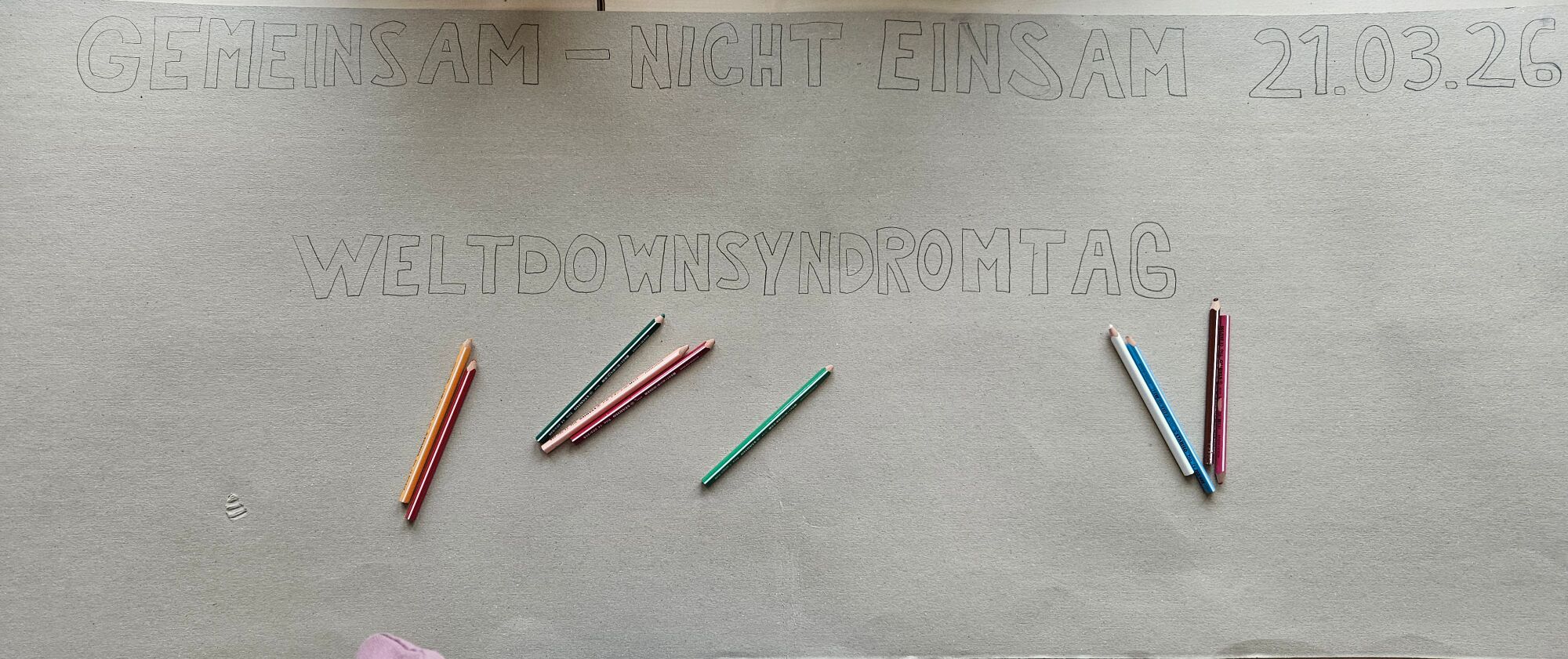 Buntstifte liegen auf einer gro&szlig;en Papierrolle